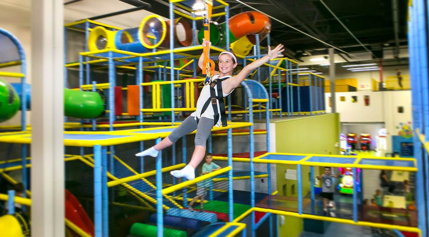 Child ziplining in indoor playground with colorful structures and tubes at Allstars Indoor Playland Edmonton